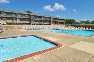 Outdoor pool with seating and gathering spaces for socializing at Woodmere apartments